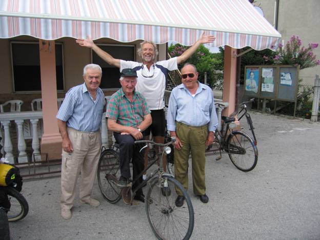 Touring cyclist celebrating meeting three old men in village square, Corona, Italy © 2012 Frosty Wooldridge